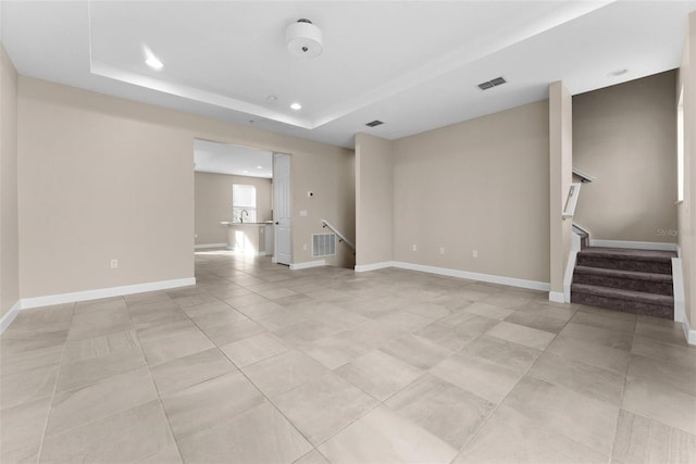 unfurnished living room with a tray ceiling and light tile patterned floors