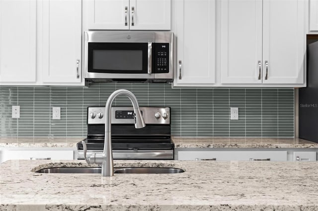 kitchen featuring stainless steel appliances, decorative backsplash, and white cabinets