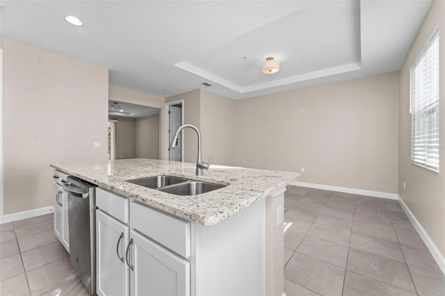 kitchen with a kitchen island with sink, sink, white cabinetry, and a raised ceiling