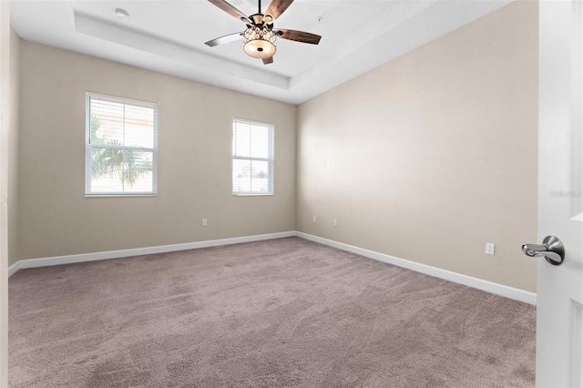 carpeted empty room with ceiling fan and a tray ceiling