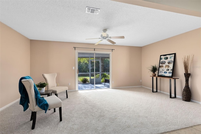 sitting room featuring a textured ceiling, light colored carpet, and ceiling fan