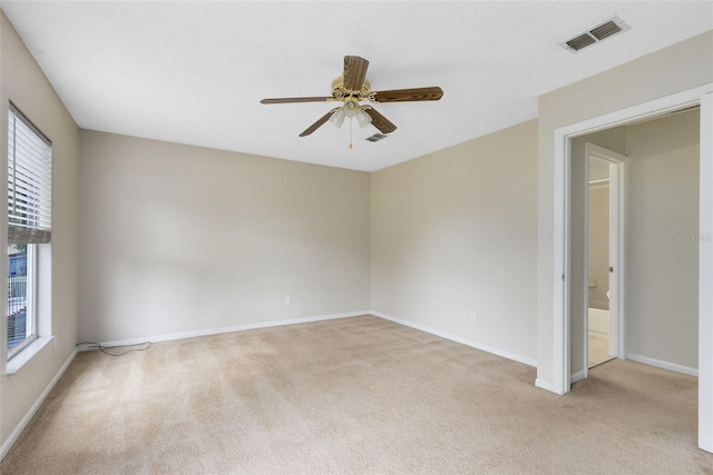 carpeted empty room with a textured ceiling, ceiling fan, and plenty of natural light