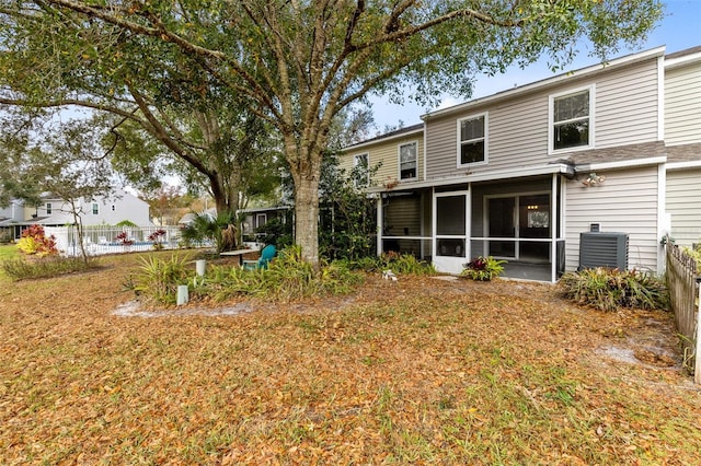 back of house featuring central air condition unit, a sunroom, and a lawn