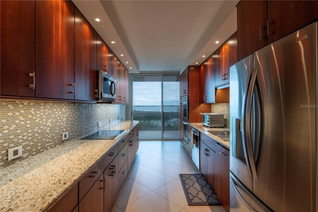 kitchen featuring tasteful backsplash, light stone countertops, expansive windows, and stainless steel appliances