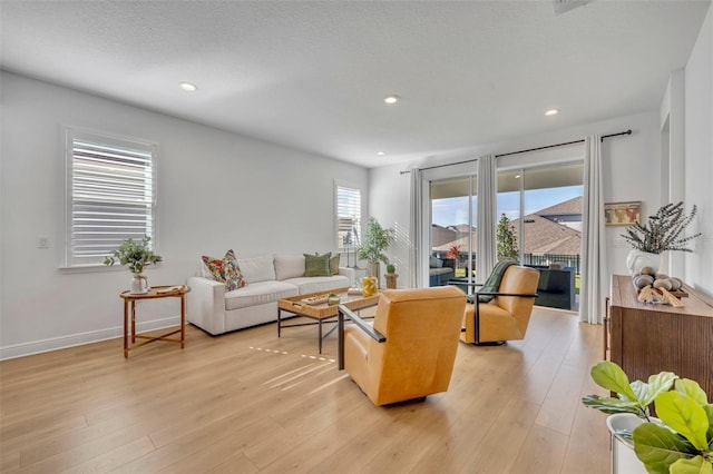 living room with a textured ceiling, light hardwood / wood-style flooring, and plenty of natural light