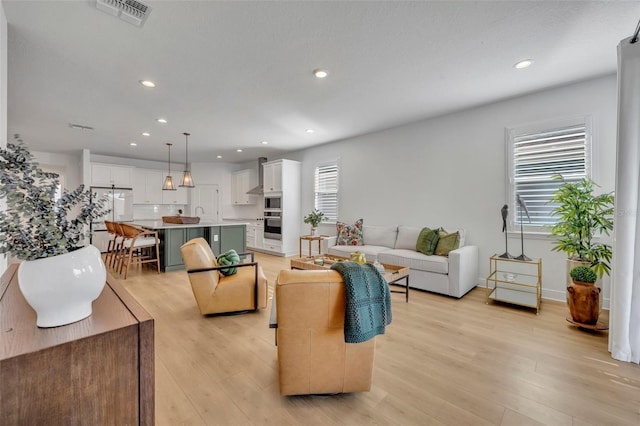 living room with a healthy amount of sunlight and light hardwood / wood-style flooring