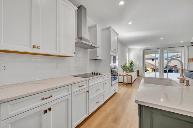 kitchen with white cabinets, sink, wall chimney exhaust hood, light stone countertops, and appliances with stainless steel finishes