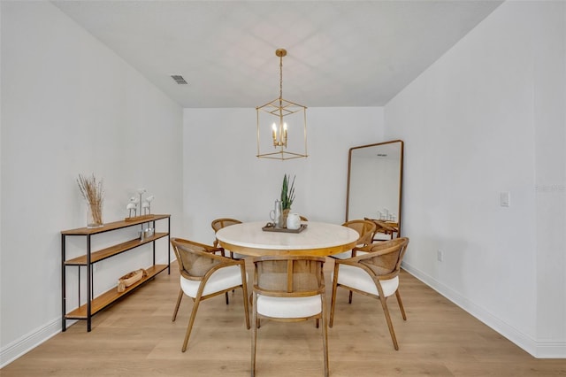 dining space with light wood-type flooring and a notable chandelier