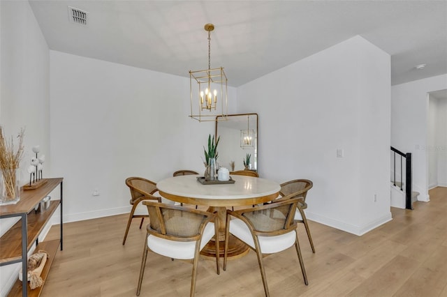 dining area with light hardwood / wood-style floors and an inviting chandelier