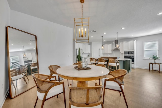 dining area with a notable chandelier, a wealth of natural light, and light hardwood / wood-style flooring