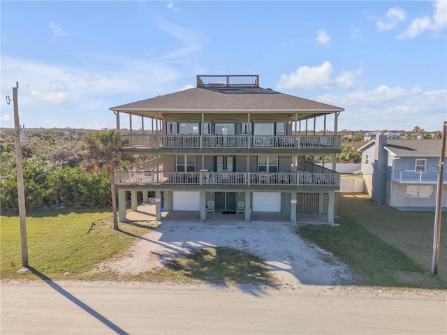 view of front facade with a garage, a front yard, a balcony, and dirt driveway