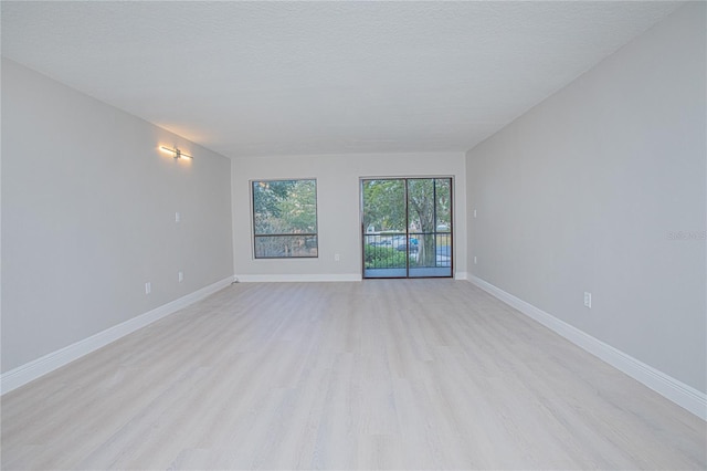 spare room featuring a textured ceiling and light hardwood / wood-style flooring