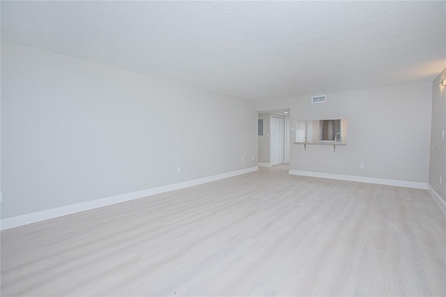 empty room with light hardwood / wood-style floors and a textured ceiling