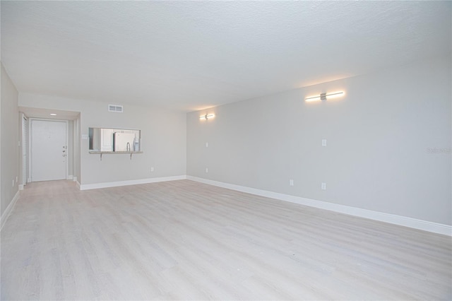 spare room with light wood-type flooring and a textured ceiling