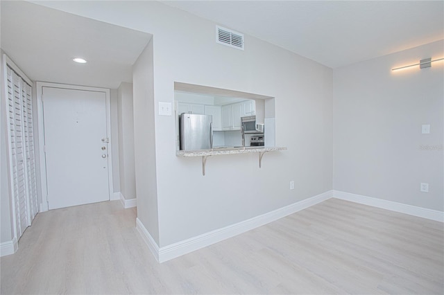 interior space with white cabinetry, a kitchen breakfast bar, light hardwood / wood-style flooring, kitchen peninsula, and appliances with stainless steel finishes