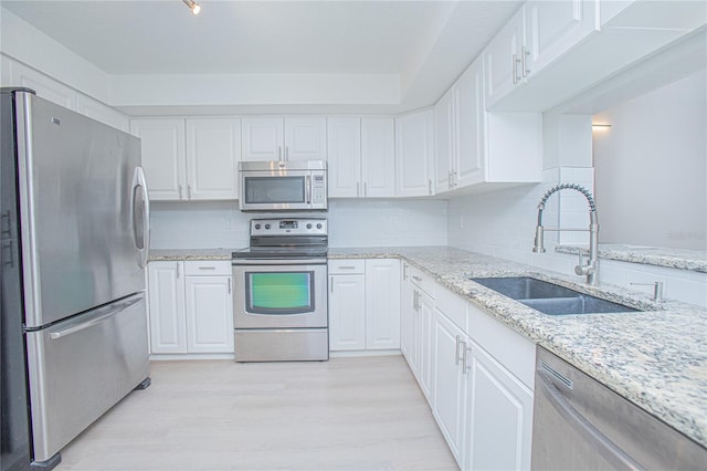 kitchen with sink, white cabinets, light wood-type flooring, and appliances with stainless steel finishes