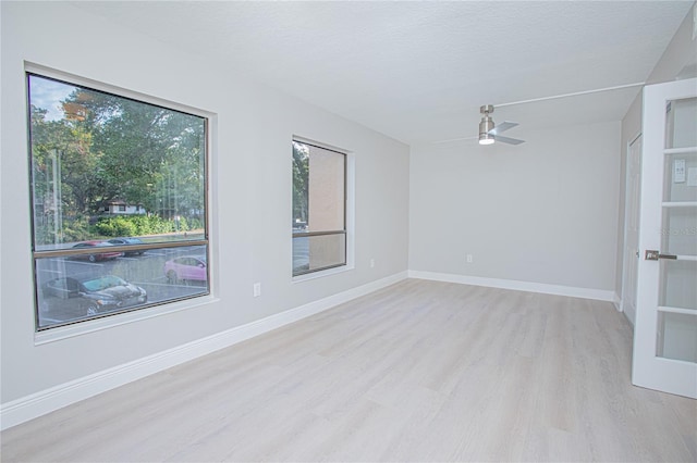 empty room with a textured ceiling, light hardwood / wood-style floors, and ceiling fan