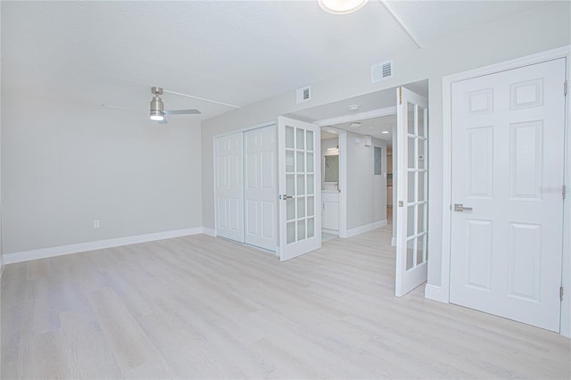 spare room featuring ceiling fan, french doors, light hardwood / wood-style floors, and a textured ceiling