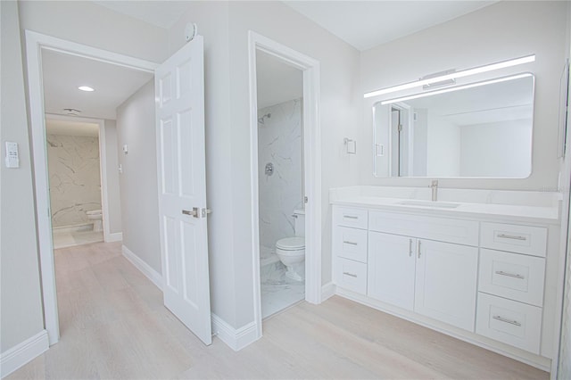 bathroom with hardwood / wood-style flooring, vanity, toilet, and a tile shower