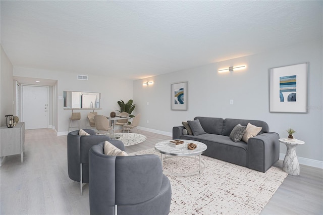 living room featuring a textured ceiling and light wood-type flooring