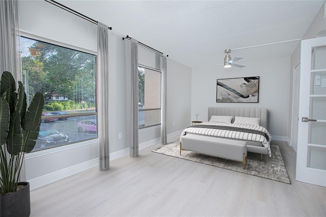 bedroom featuring a textured ceiling, ceiling fan, light hardwood / wood-style flooring, and multiple windows