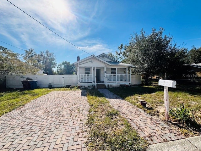 bungalow-style home featuring covered porch and a front lawn