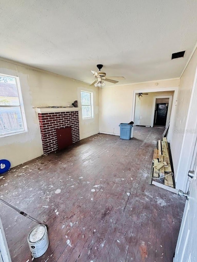 unfurnished living room with ceiling fan, a fireplace, a textured ceiling, and hardwood / wood-style flooring