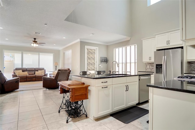 kitchen with a healthy amount of sunlight, stainless steel appliances, white cabinetry, and a center island with sink