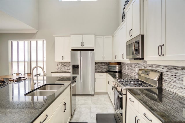 kitchen with dark stone countertops, sink, white cabinetry, and stainless steel appliances