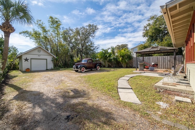 view of yard with a gazebo, a garage, an outdoor structure, and a patio area