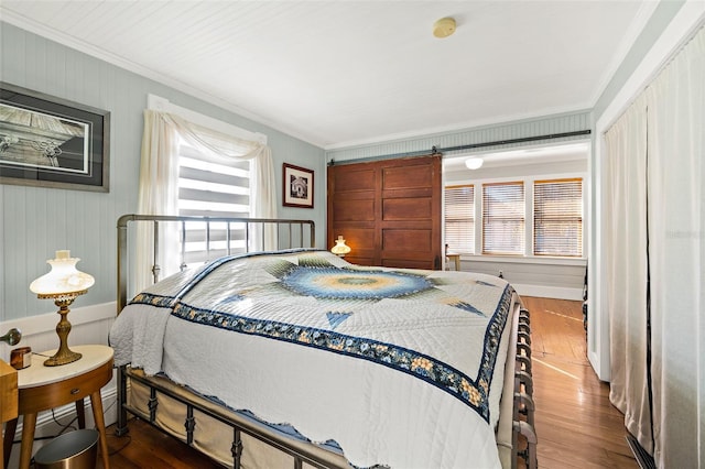 bedroom featuring crown molding, wood-type flooring, and a barn door