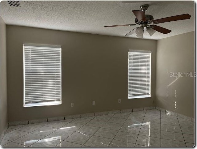 tiled spare room with ceiling fan and a textured ceiling