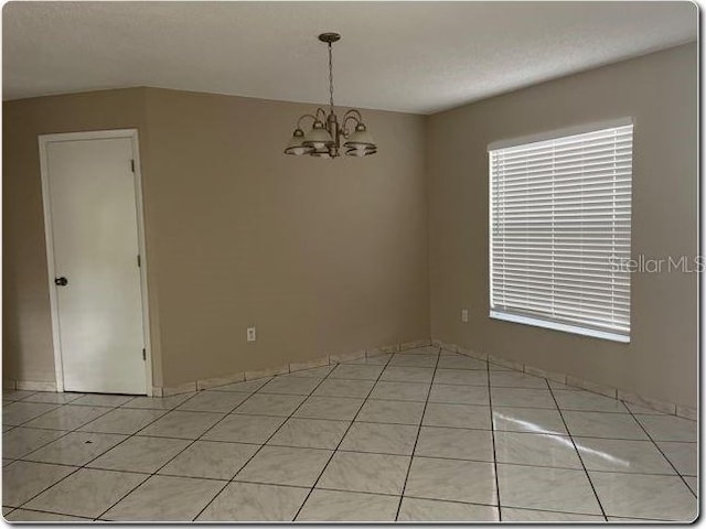 spare room with light tile patterned floors and a notable chandelier