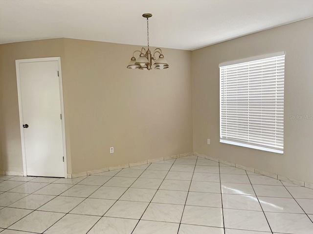 empty room with light tile patterned floors and a chandelier