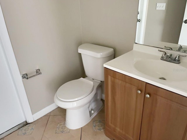 half bathroom with toilet, tile patterned floors, baseboards, and vanity