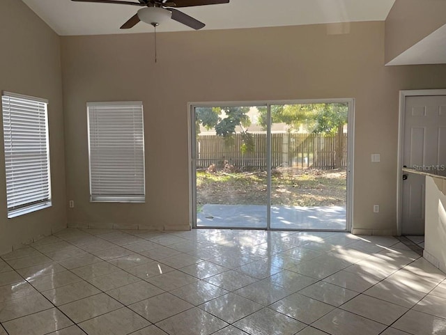 tiled spare room featuring baseboards and a ceiling fan