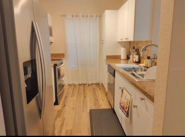 kitchen with backsplash, sink, appliances with stainless steel finishes, light hardwood / wood-style floors, and white cabinetry