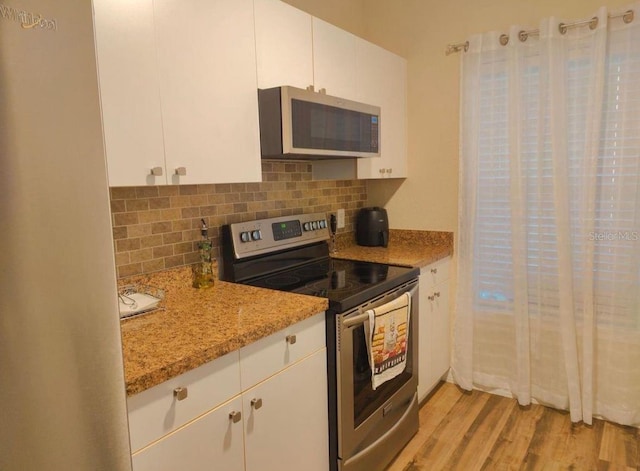 kitchen featuring white cabinets, light wood-type flooring, stainless steel appliances, and light stone countertops