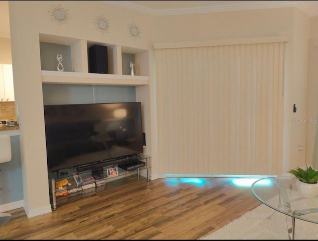 living room with hardwood / wood-style flooring, built in shelves, and ornamental molding