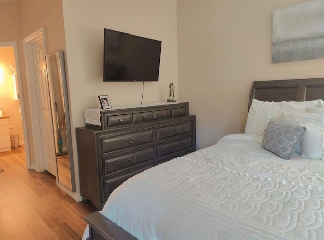 bedroom featuring ensuite bath and light hardwood / wood-style flooring