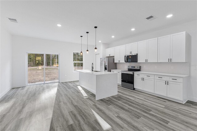 kitchen with white cabinetry, an island with sink, stainless steel appliances, and decorative light fixtures