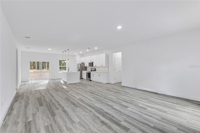 unfurnished living room with sink and light hardwood / wood-style flooring