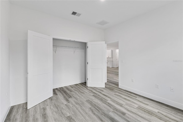 unfurnished bedroom featuring a closet and light wood-type flooring