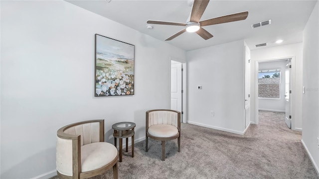 living area with light carpet and ceiling fan