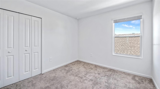 unfurnished bedroom with a closet and light colored carpet