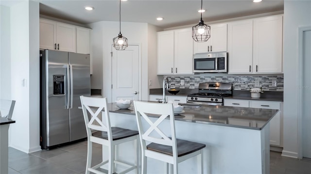 kitchen with stainless steel appliances, a center island, pendant lighting, white cabinetry, and backsplash