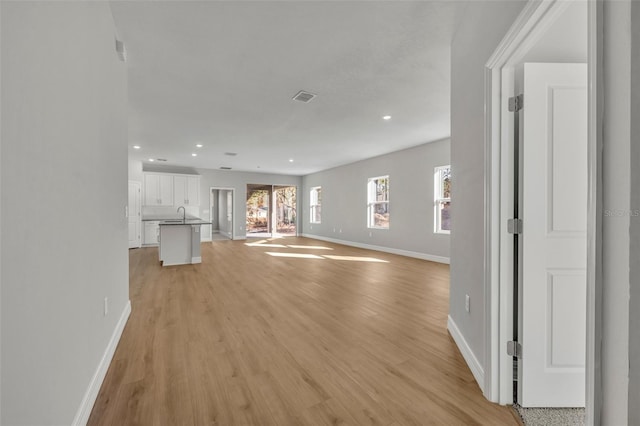 unfurnished living room with light wood-type flooring and sink