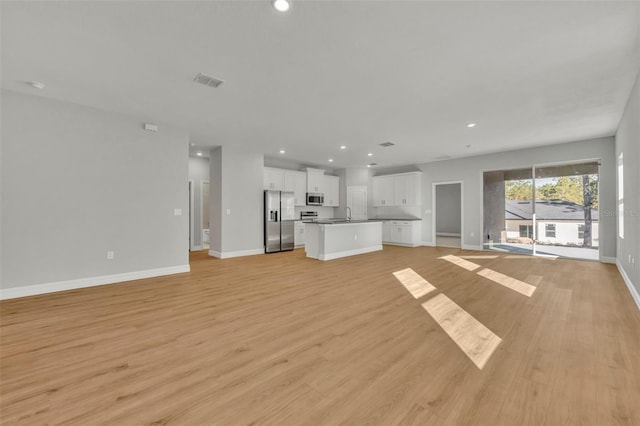 unfurnished living room with sink and light wood-type flooring