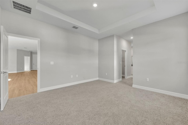 empty room featuring light colored carpet and a tray ceiling