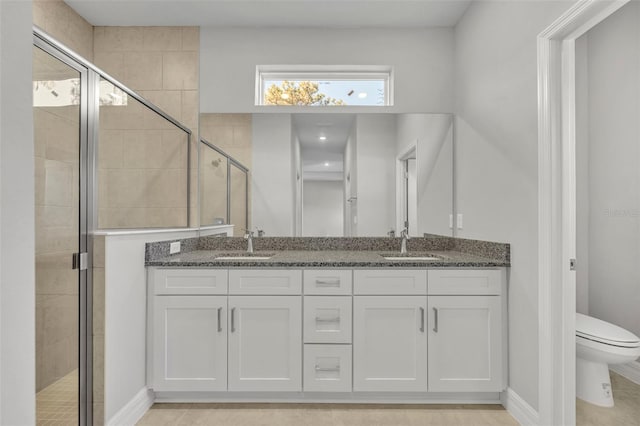 bathroom featuring tile patterned floors, vanity, toilet, and a shower with shower door